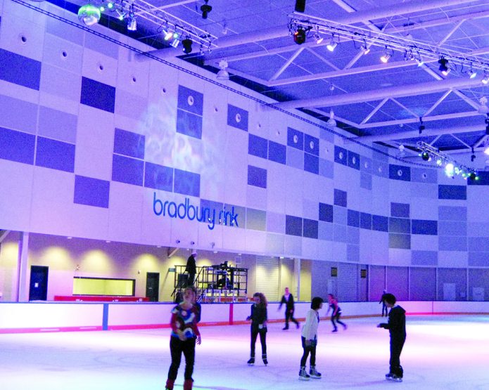 An image of the interior of the Docklands Icehouse ice-rink with a group of people skating on the ice