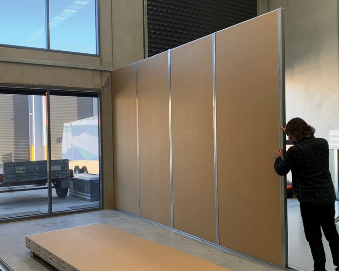 Person installing a compressed straw panel partition wall in a warehouse space